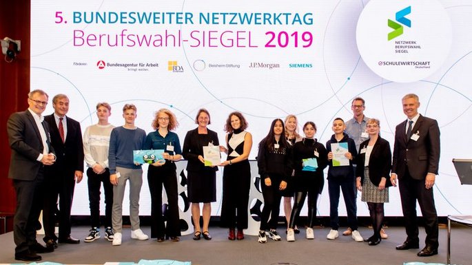 mehrere Personen vor einem großen Plakat mit der Aufschrift des 5. Bundesweiten Netzwerktags
