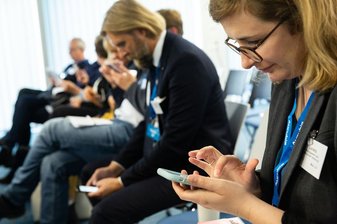 sitzende Personen schauen auf ihr Handy